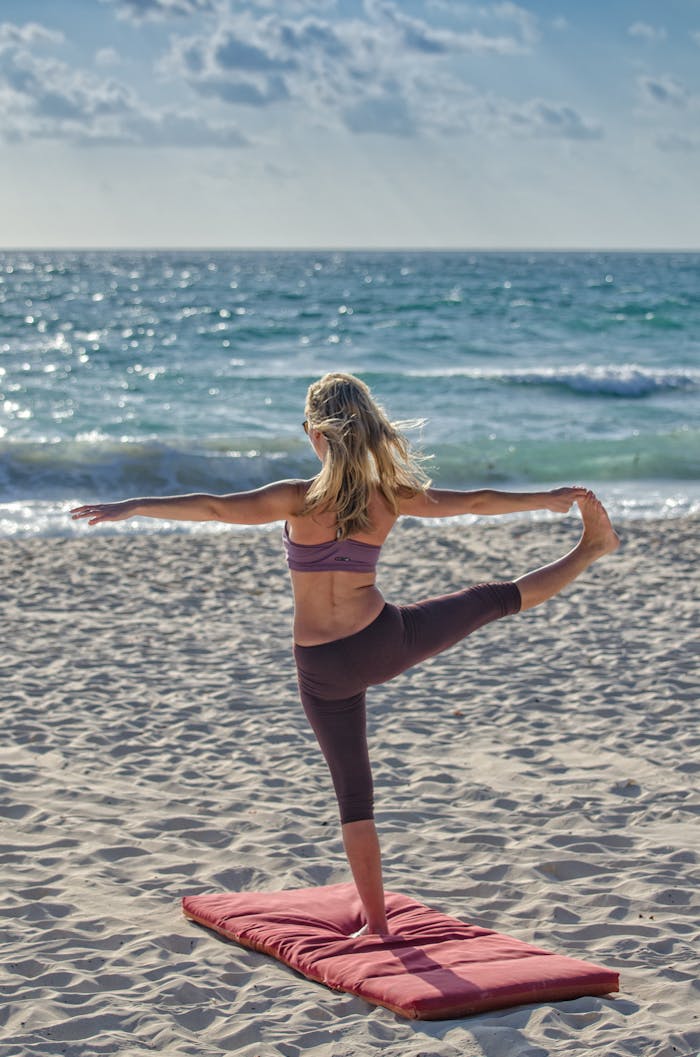 our-services-1 A woman performs yoga on a sandy beach at sunrise, embracing wellness and tranquility.